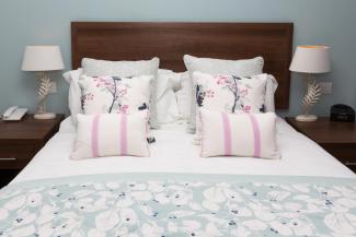 Cushions and pillows on the bed inside a Superior Sea View with Balcony room at Sandy Cove Hotel