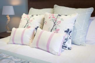 Cushions and pillows on the bed inside a Superior Sea View with Balcony room at Sandy Cove Hotel