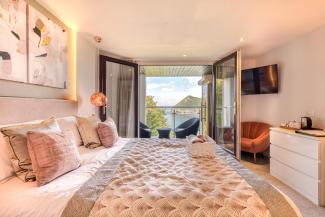 The interior of and executive sea view room with balcony at Sandy Cove Hotel showing the bed and balcony with a view over the bay