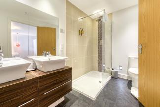 The rainforest shower and twin basins in the bathroom of a Deluxe Sea View with Balcony room at Sandy Cove Hotel