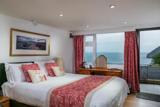 A bed and sea view from one of Sandy Cove Hotel's Standard Rooms