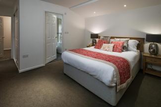 The bed and door to the en-suite bathroom in a Standard Room at Sandy Cove Hotel