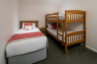 A single bed and bunk beds inside one of Sandy Cove Hotel's Standard Rooms