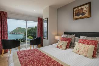The bed and seating area with a view over the bay in one of the Standard Rooms at Sandy Cove Hotel